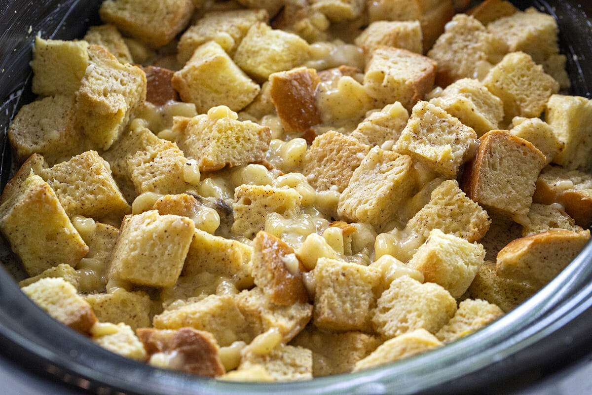 Cubed bread in a slow cooker with custard poured over it.