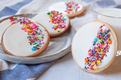 Royal icing and sprinkles decorate circle sugar cookies.