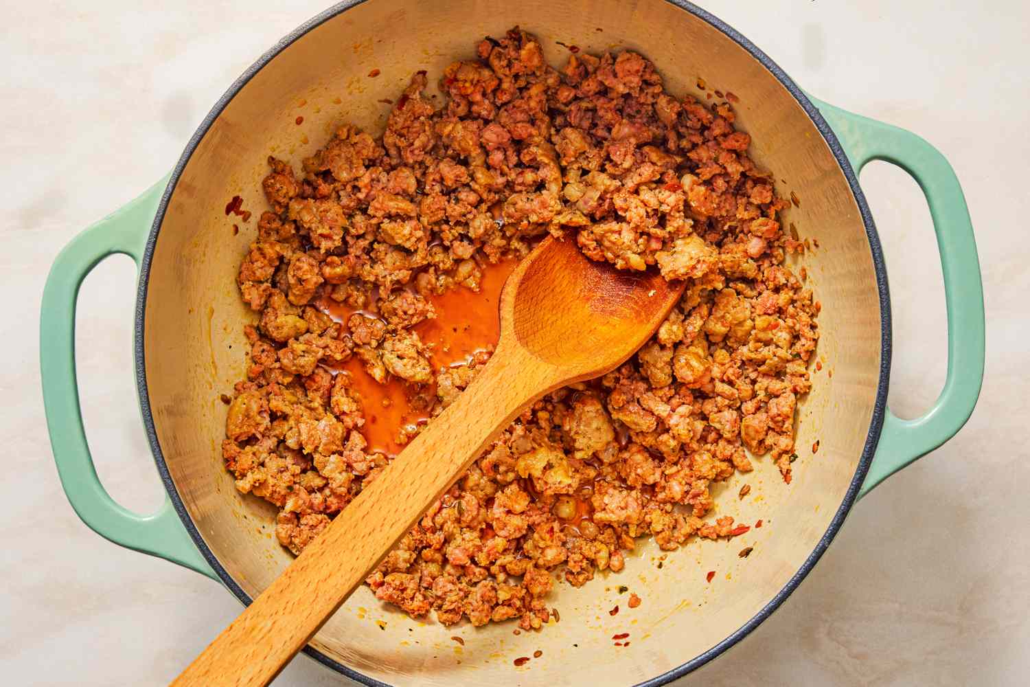 Ground meat browning in a pot with a wooden spoon for the 5-Ingredient Braised Cabbage “Lasagna” recipe