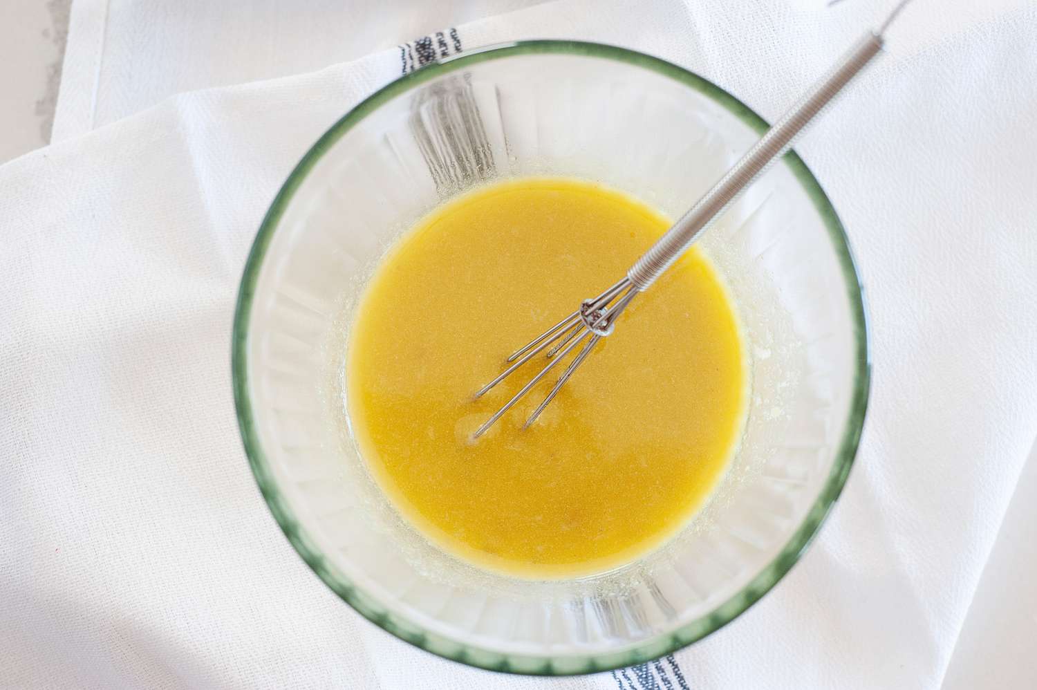 Whisking in oil to make Anchovy Mustard Salad Dressing.