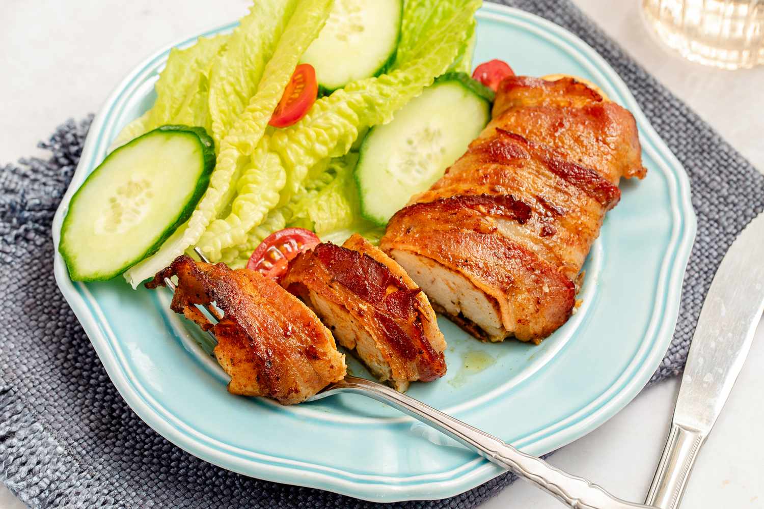 Bacon-Wrapped Chicken on a plate with a small side salad and a knife and fork