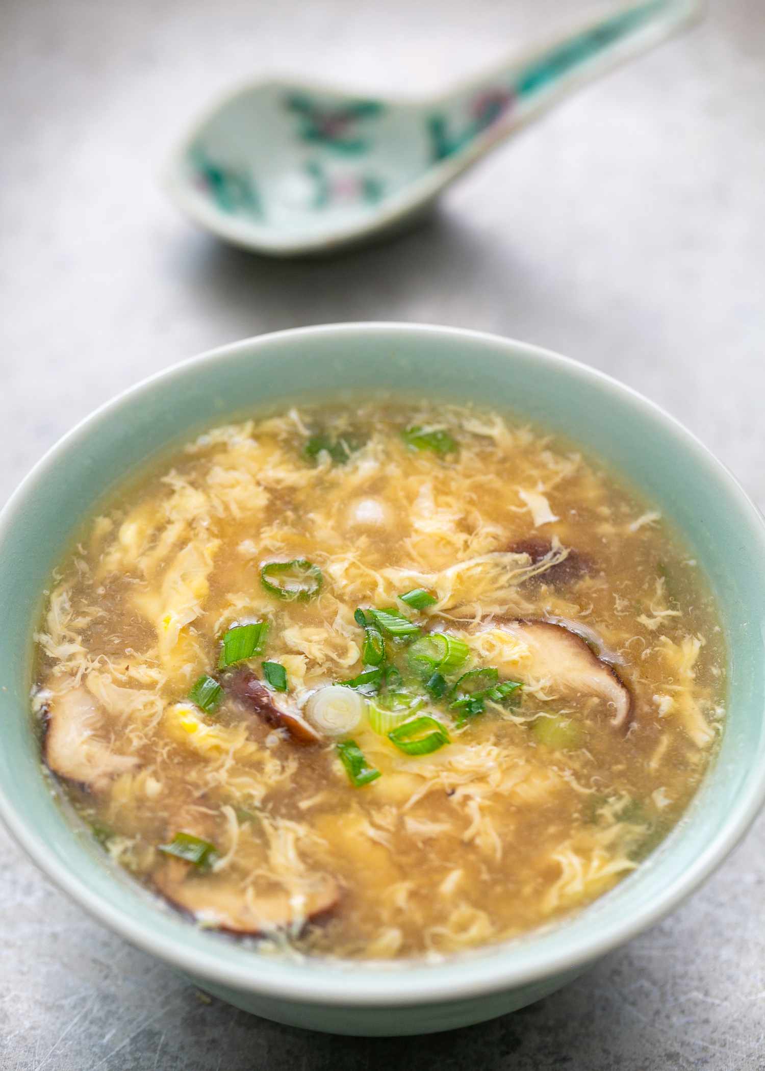Bowl of egg drop soup with a spoon in the background