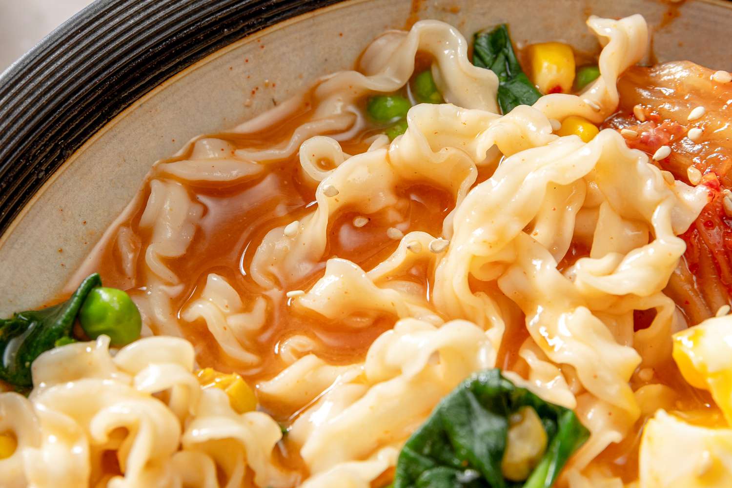 A bowl of noodle soup with vegetables in a close-up view