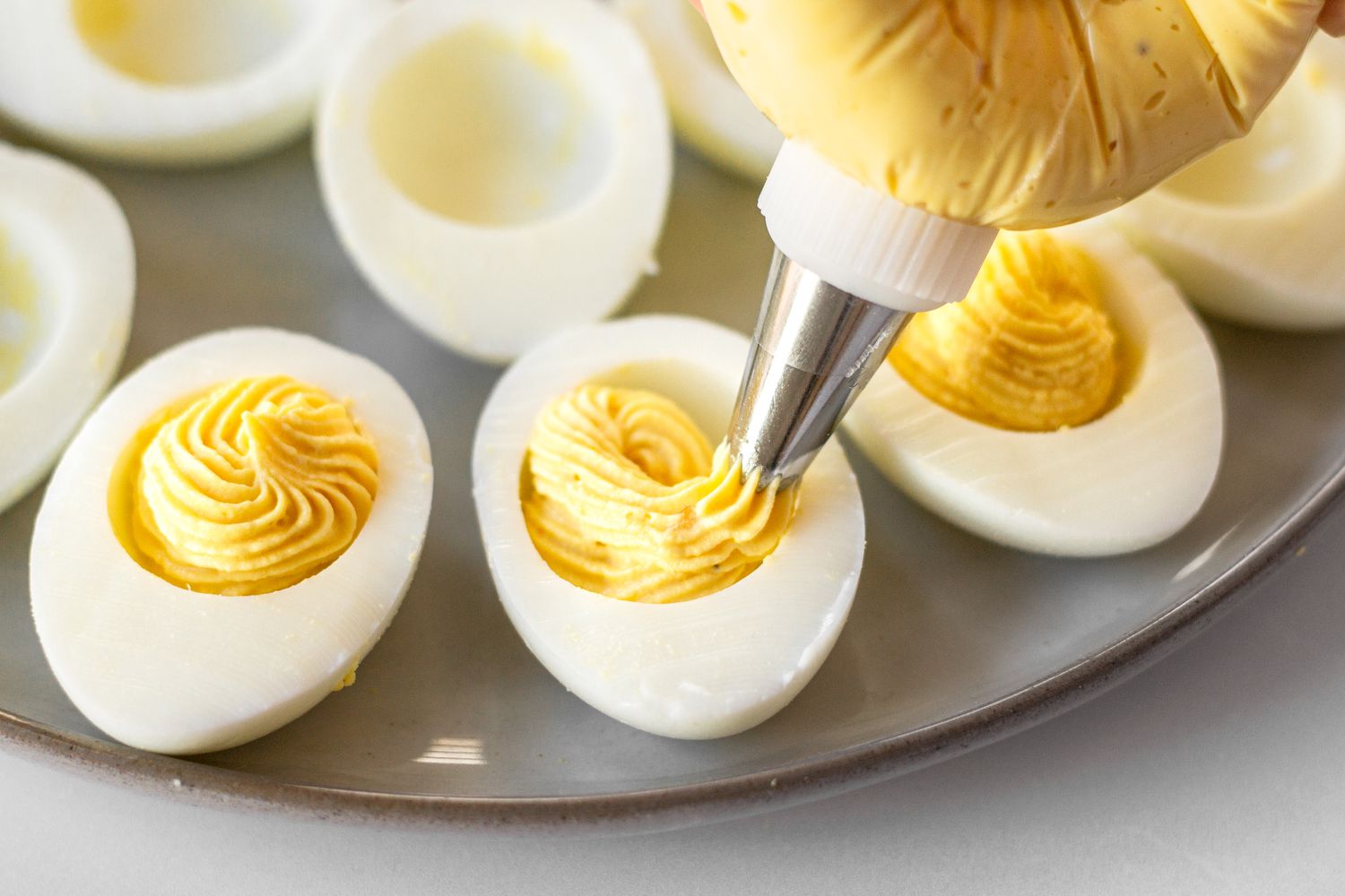 Piping the filling into the hard boiled egg to make Classic Deviled Eggs.