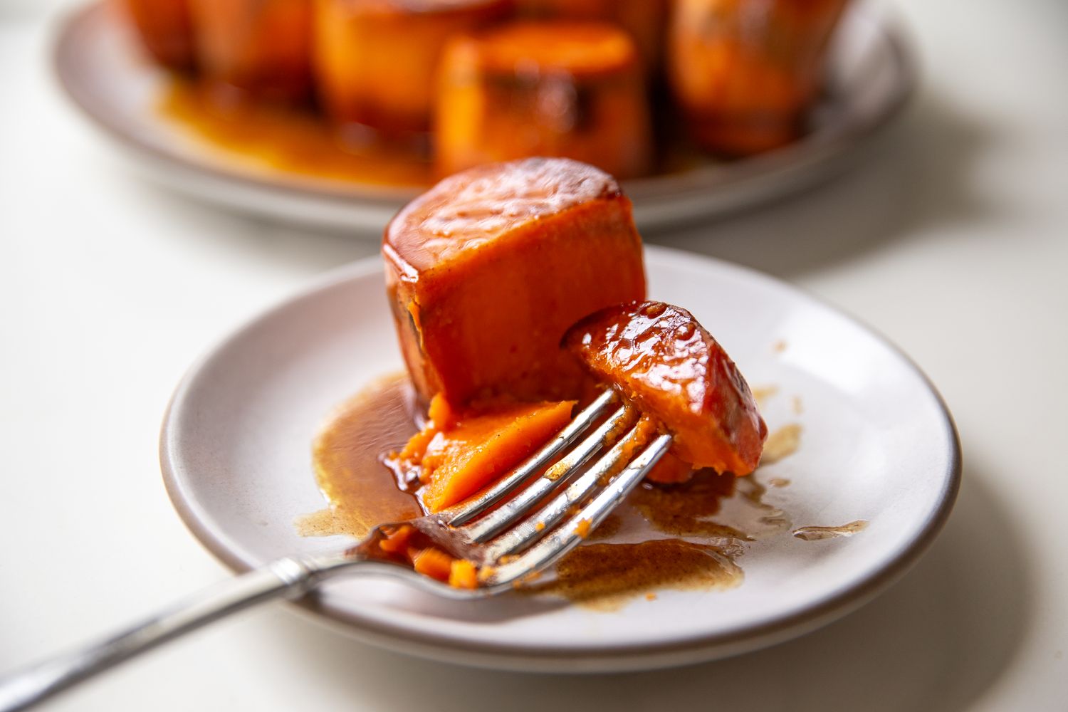 Slices of sweet potatoes on a plate with one piece being cut with a fork