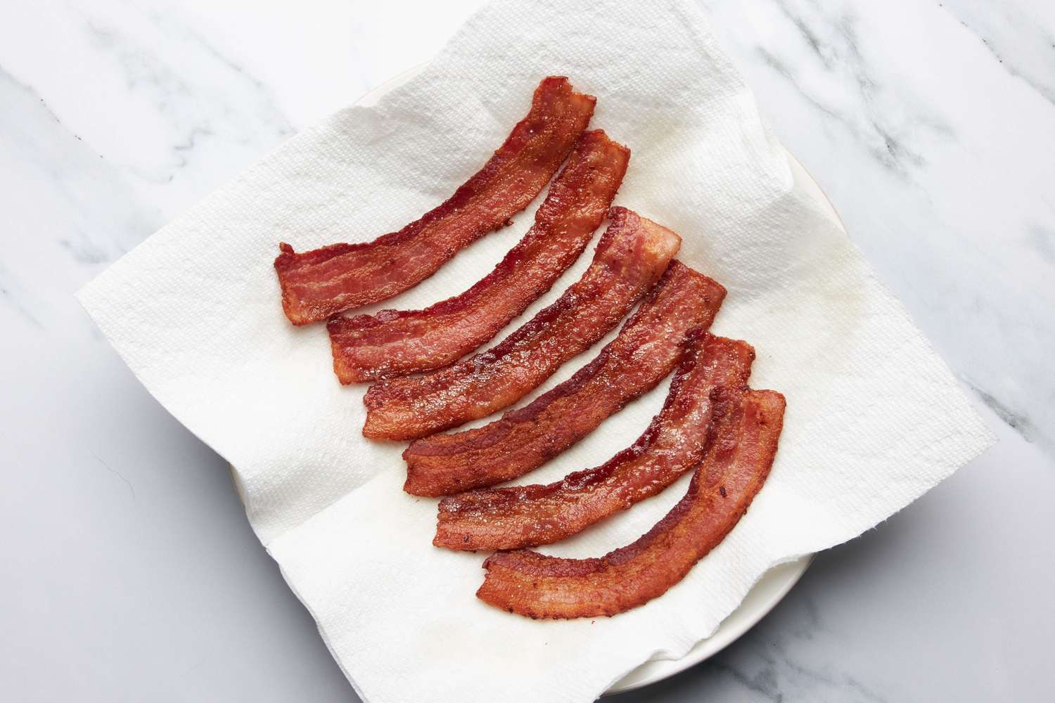 Cooked bacon on a paper towel covered plate for jalapeÃ±o popper grilled cheese recipe