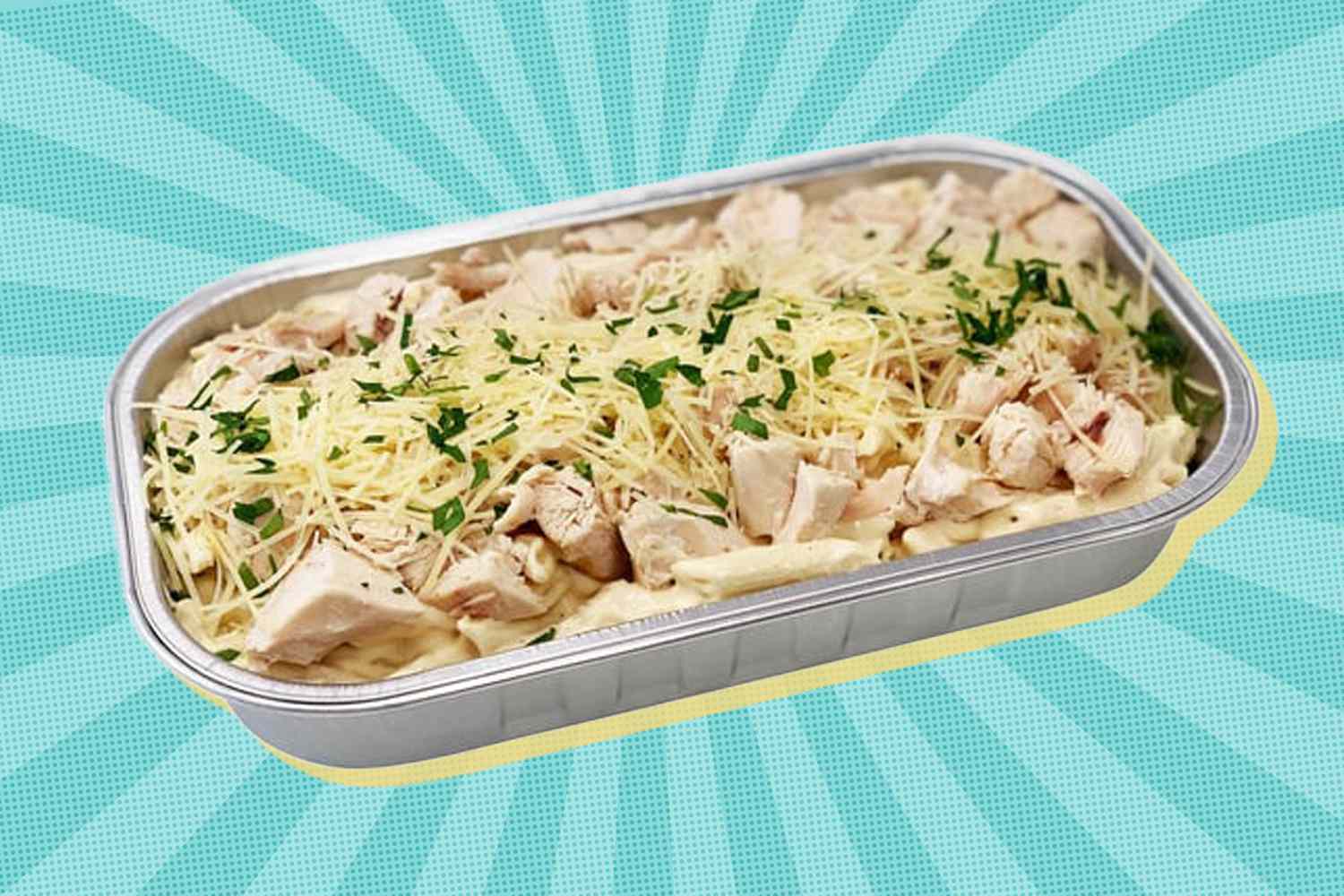 Tray of prepared chicken alfredo pasta with shredded cheese and herbs on top