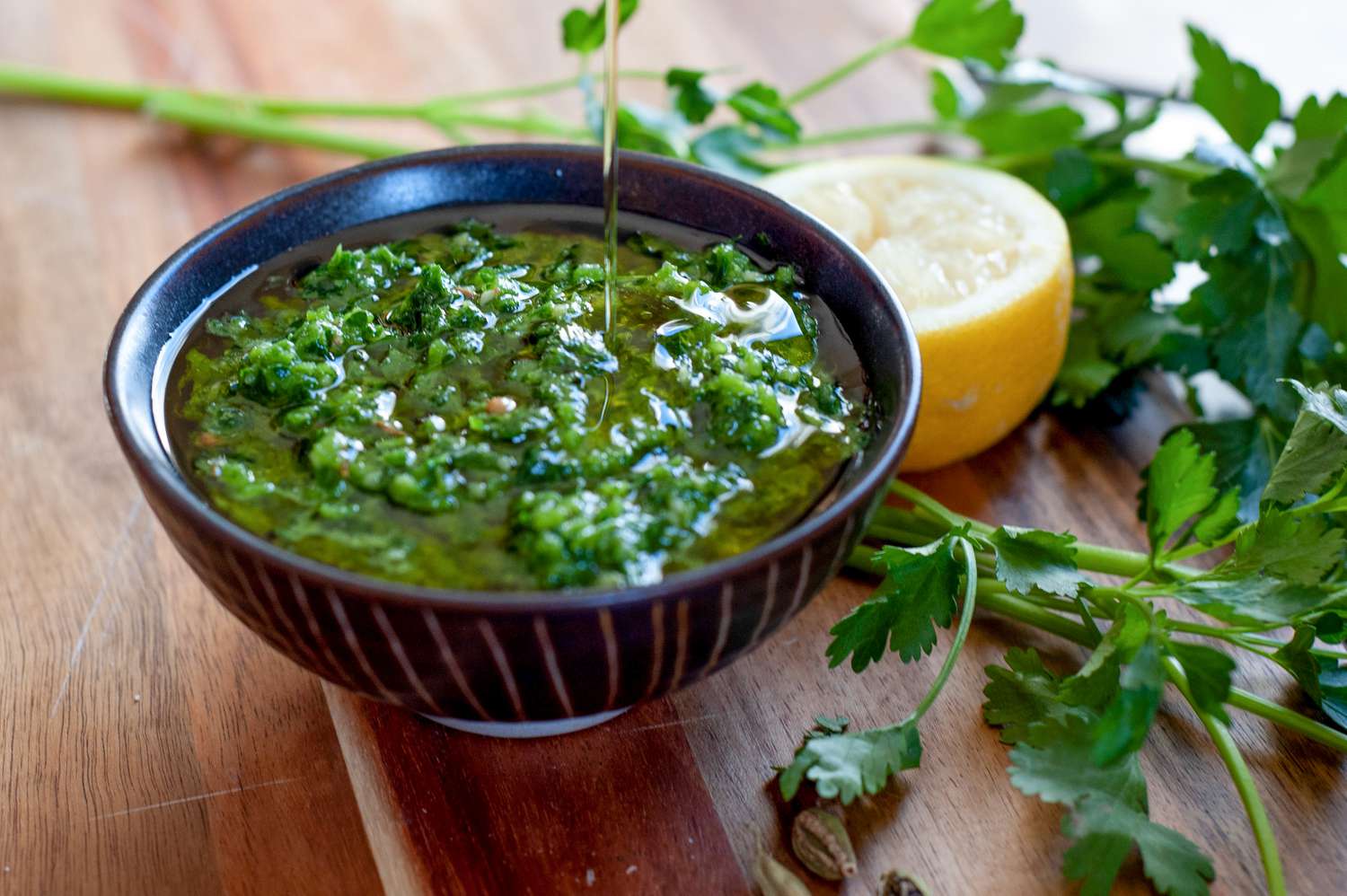 Zhoug in a small black bowl with olive oil on top.
