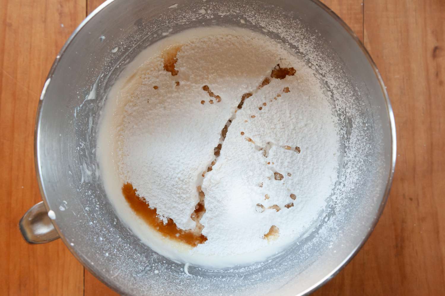 Adding vanilla to a stand mixer for the best whipped cream frosting.