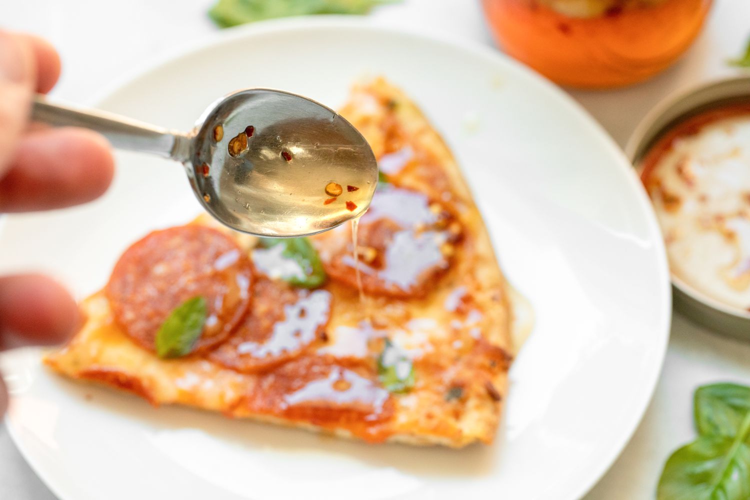 Fermented Garlic Honey on a Spoon, Drizzled on a Slice of Pizza