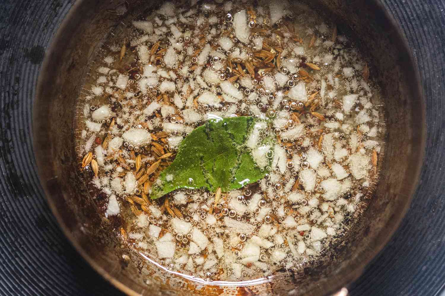 Alliums whole spices and herbs blooming in oil