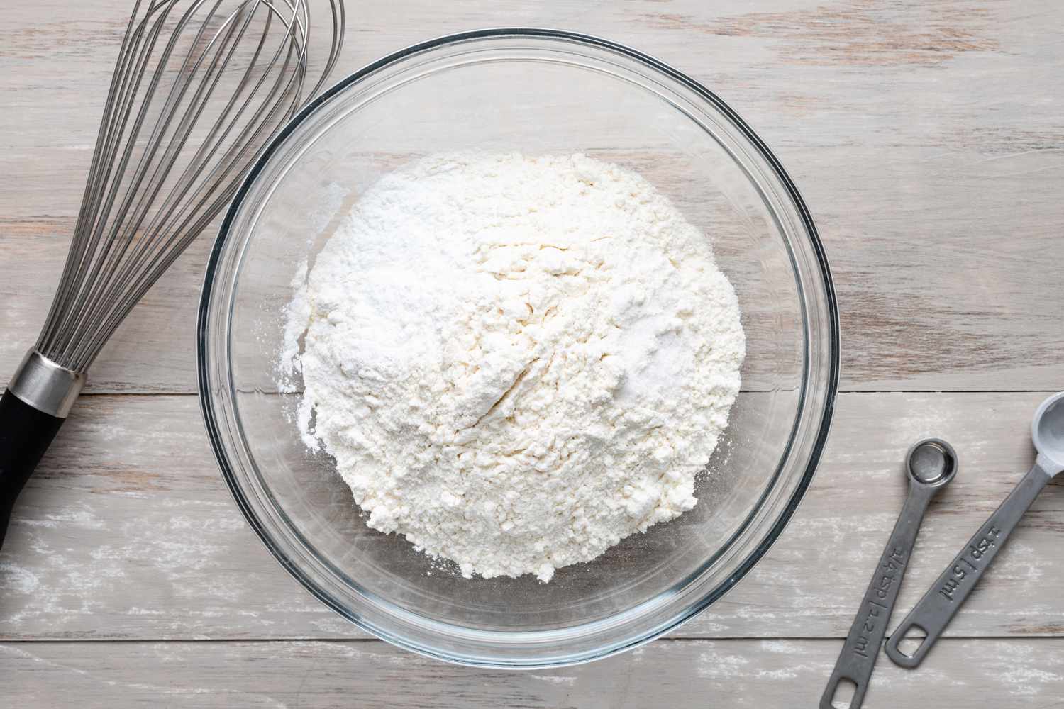 Bowl of Dry Ingredients Surrounded by a Whisk and Measuring Spoons for Buckeye Pancake Recipe