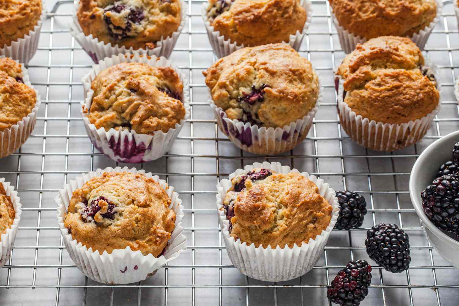 Blackberry Muffins on a Cooling Rack with a Bowl of Blackberries Next to It