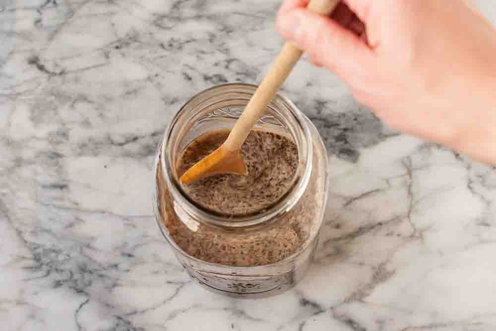 A wooden spoon stirring the water and coffee grounds mixture 