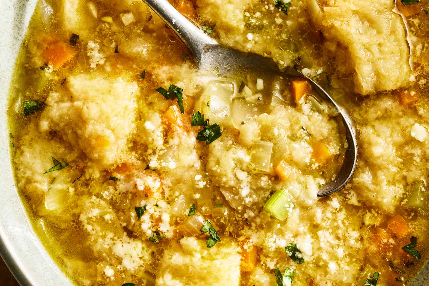 A bowl of pancotto soup with bread vegetables and a spoon