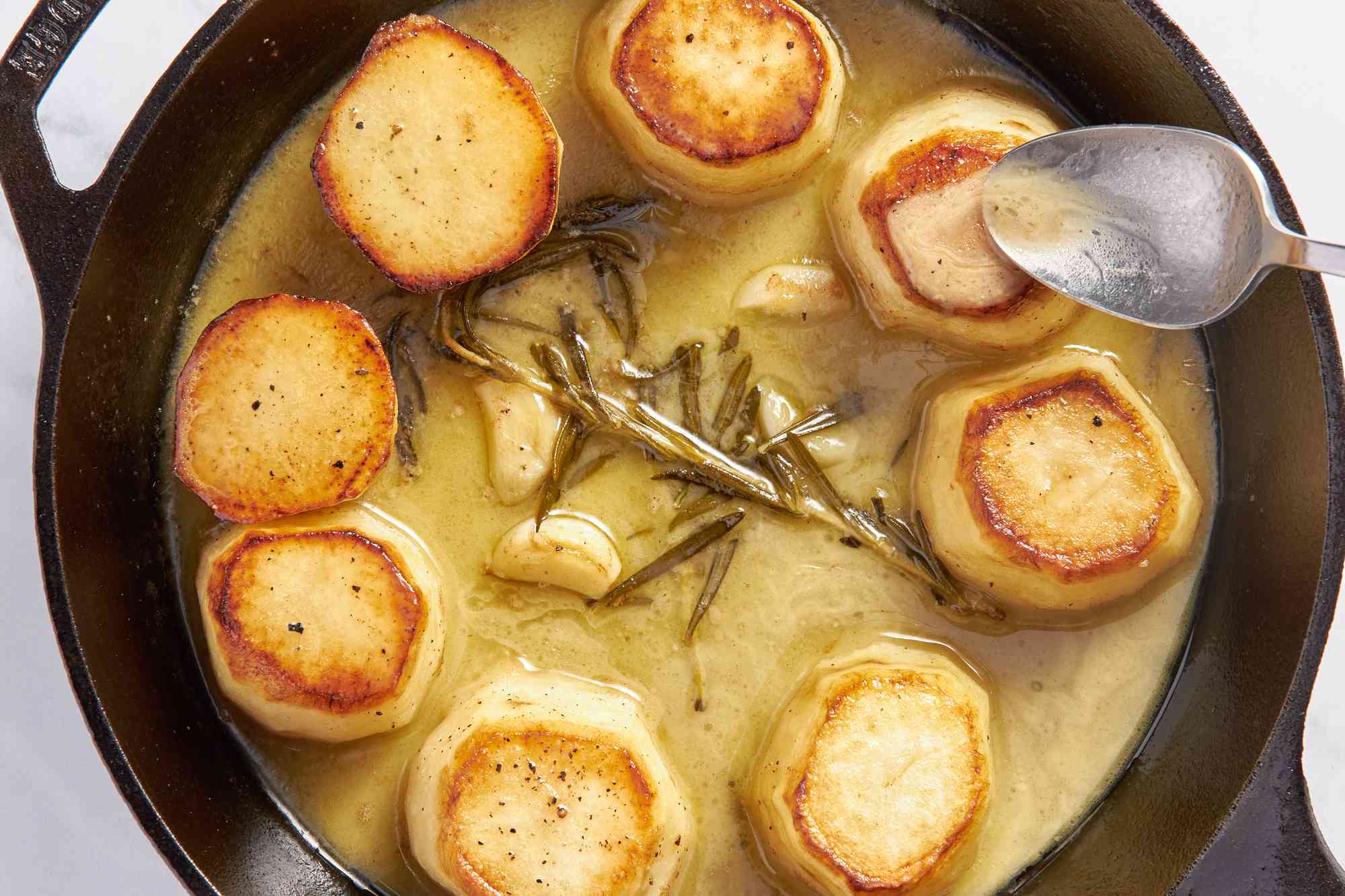 Garlic rosemary sauce spooned onto fondant potatoes (both are in the same skillet)