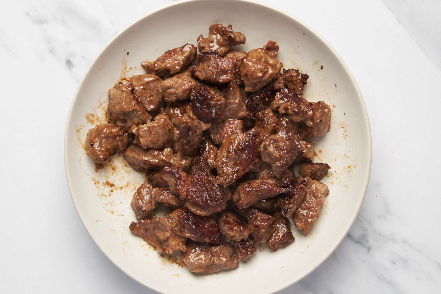 Browned chuck roast pieces resting on a plate for carne picada recipe