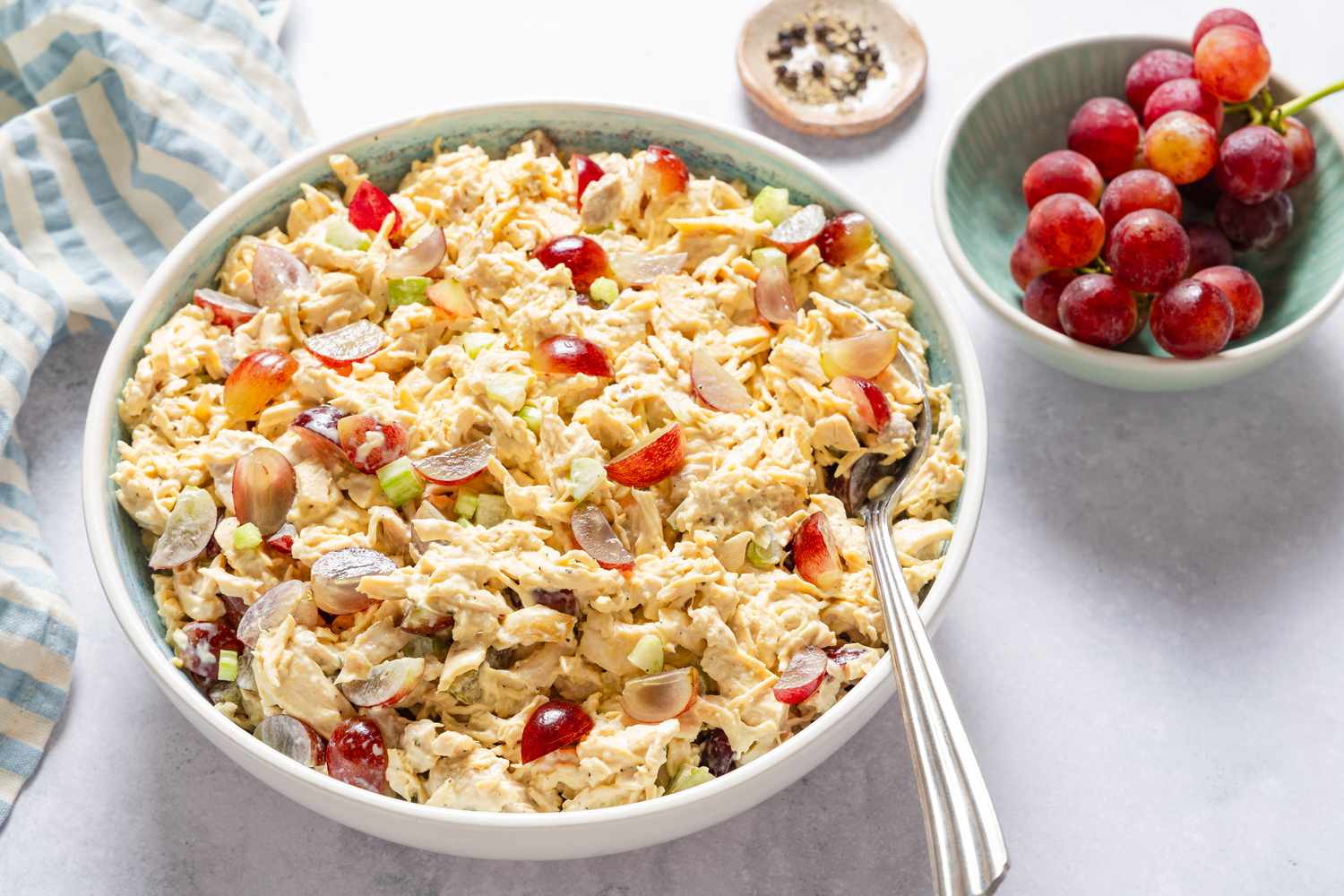 Chicken Salad with Grapes in a bowl with a large spoon, grapes on the side