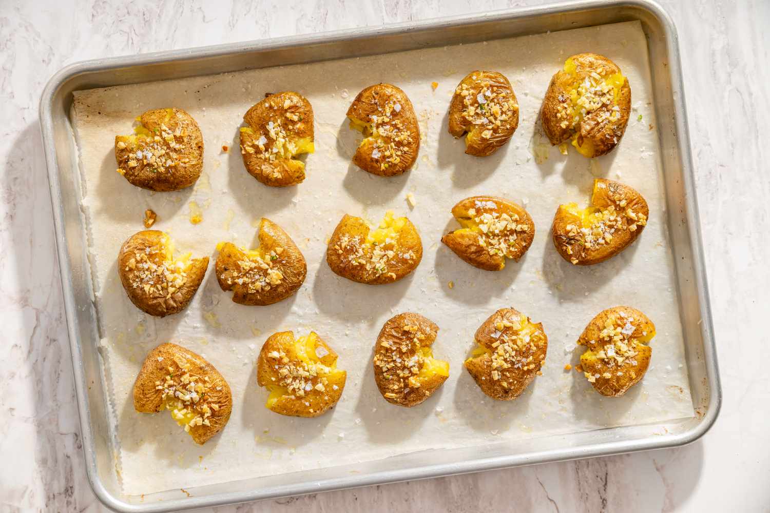 Tray of smashed potatoes topped with seasoning
