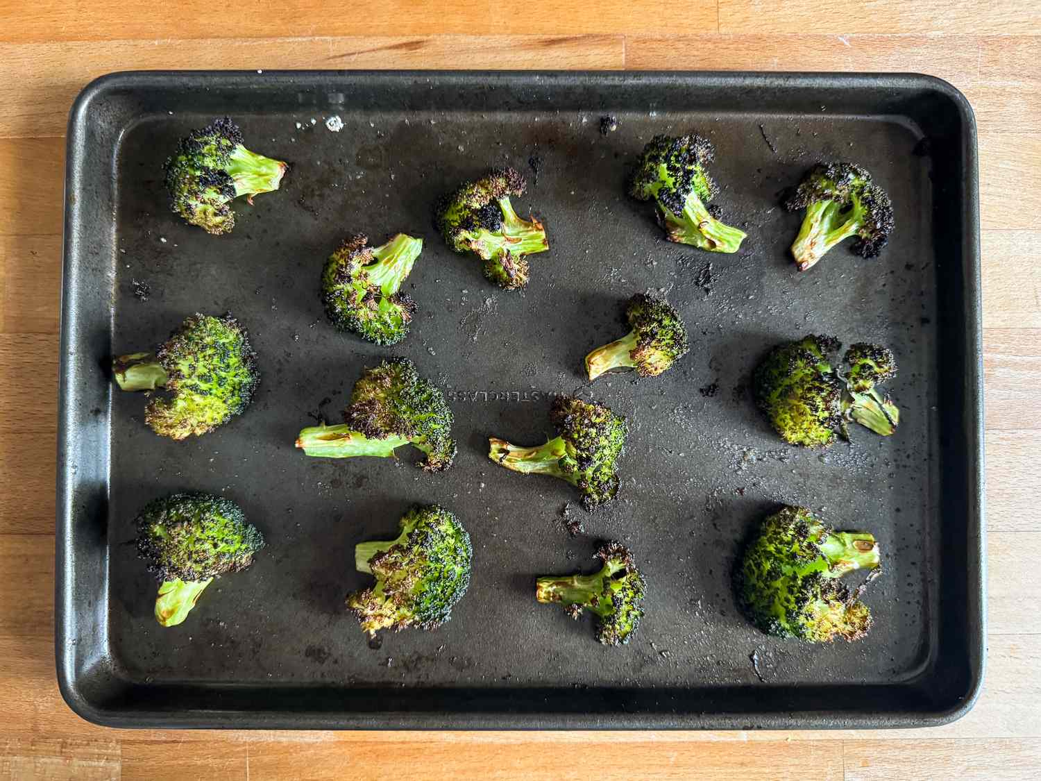 Roasted broccoli florets arranged on a baking tray
