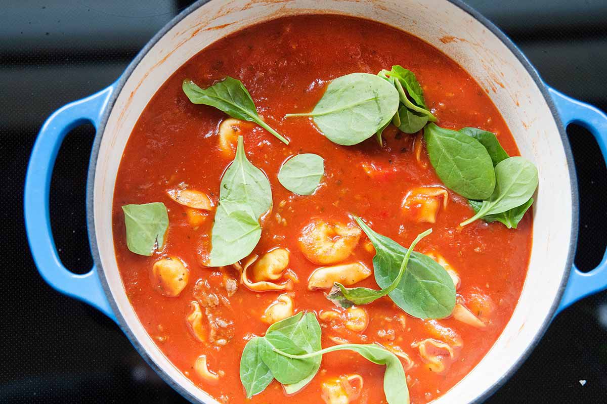 Tomato Spinach Tortellini Soup - shot of tortellini soup in pot with spinach