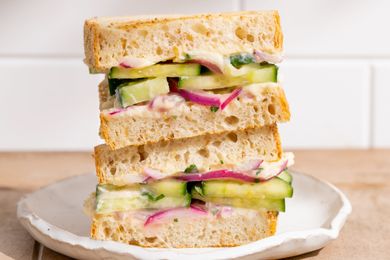 Stacked cucumber and red onion sandwiches on a white plate