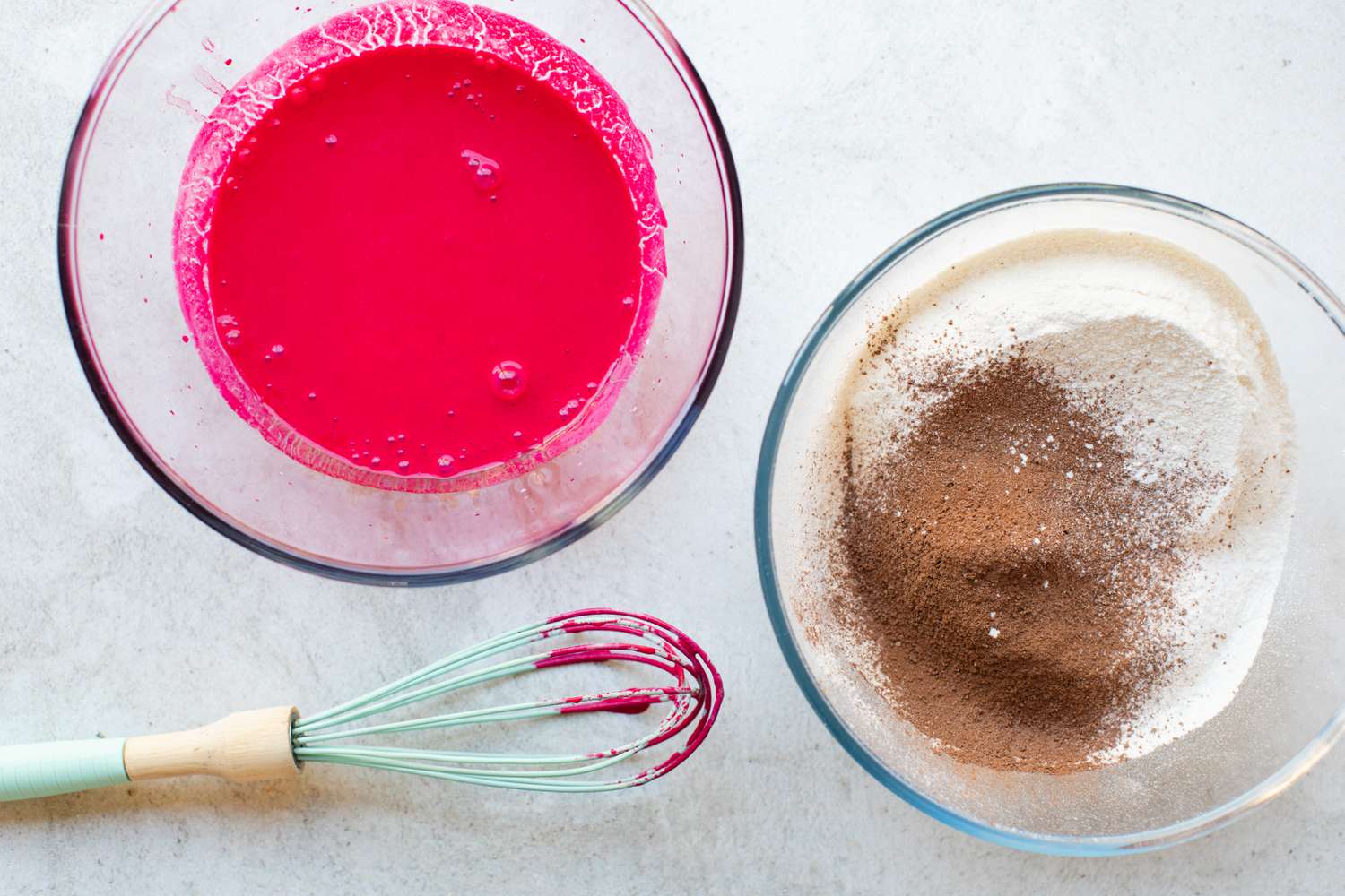 Wet and dry ingredients in separate bowls with a whisk next to it to make the best red velvet cake recipe