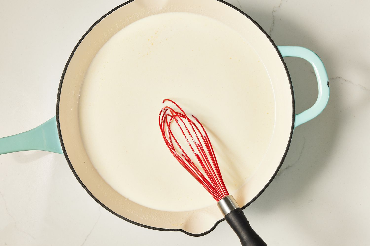 Heavy cream whisked into the roux mixture in the skillet for copycat Olive Garden Alfredo recipe 