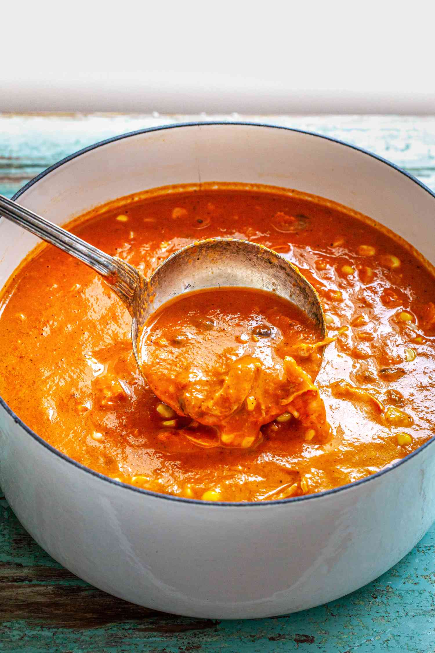 Dutch Oven of Creamy Chicken Enchilada Soup with Some Poured into the Pot from a Ladle 