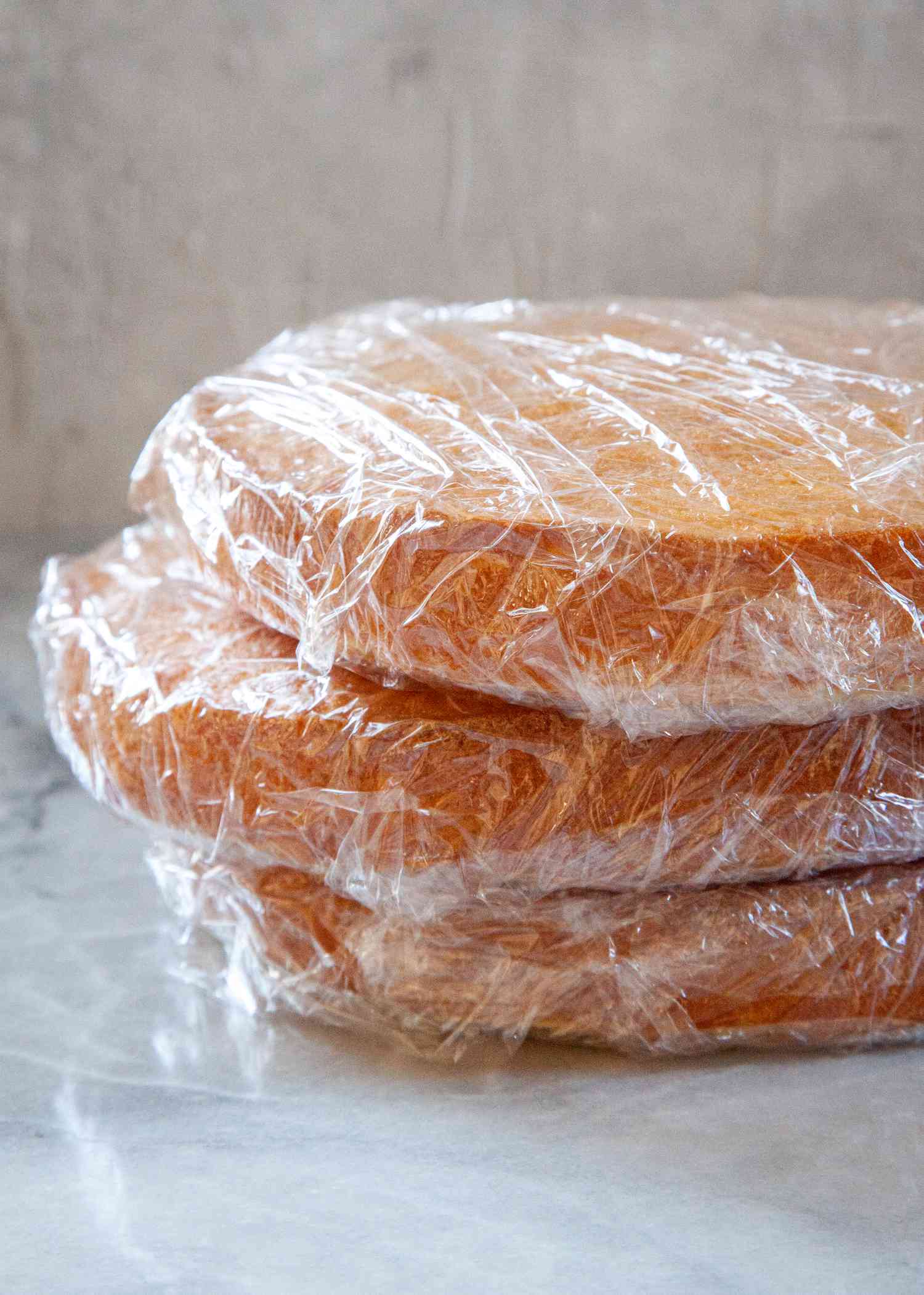 Three plastic wrapped cake layers to show how to freeze cake.