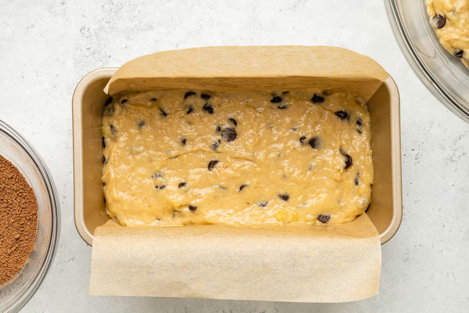 Half of the Chocolate Chip Banana Bread Coffee Cake Batter Added to Parchment Paper Lined Loaf Pan