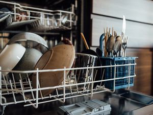 A dishwasher filled with bowls, plates, glasses, and silverware. 
