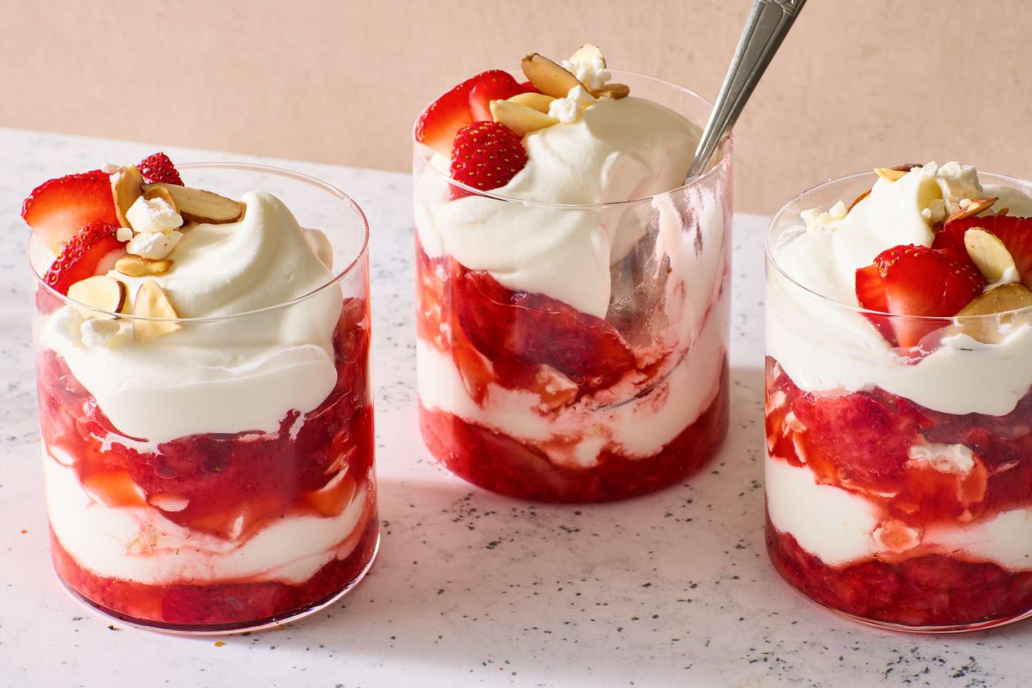 Three glasses of strawberry Eton mess topped with whipped cream and almonds