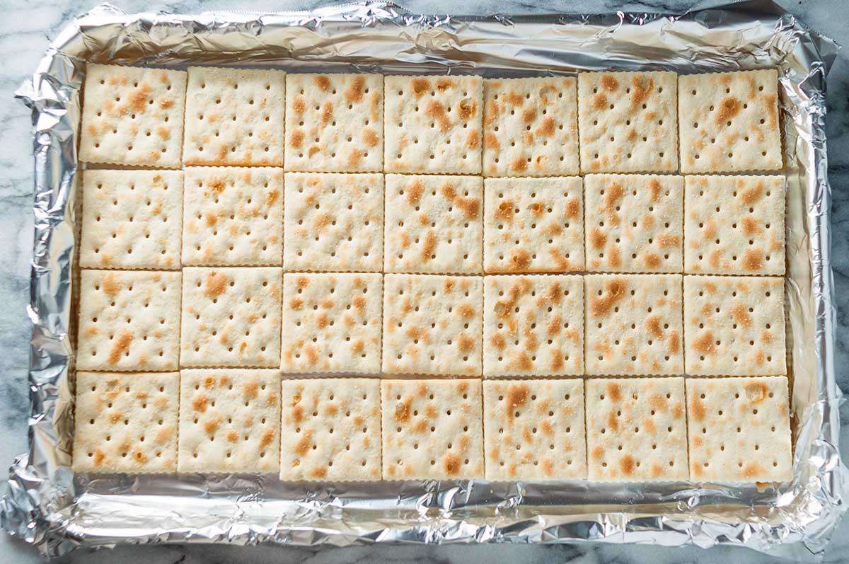 A foiled baking sheet with saltine crackers placed flat and perfectly filling the bottom 