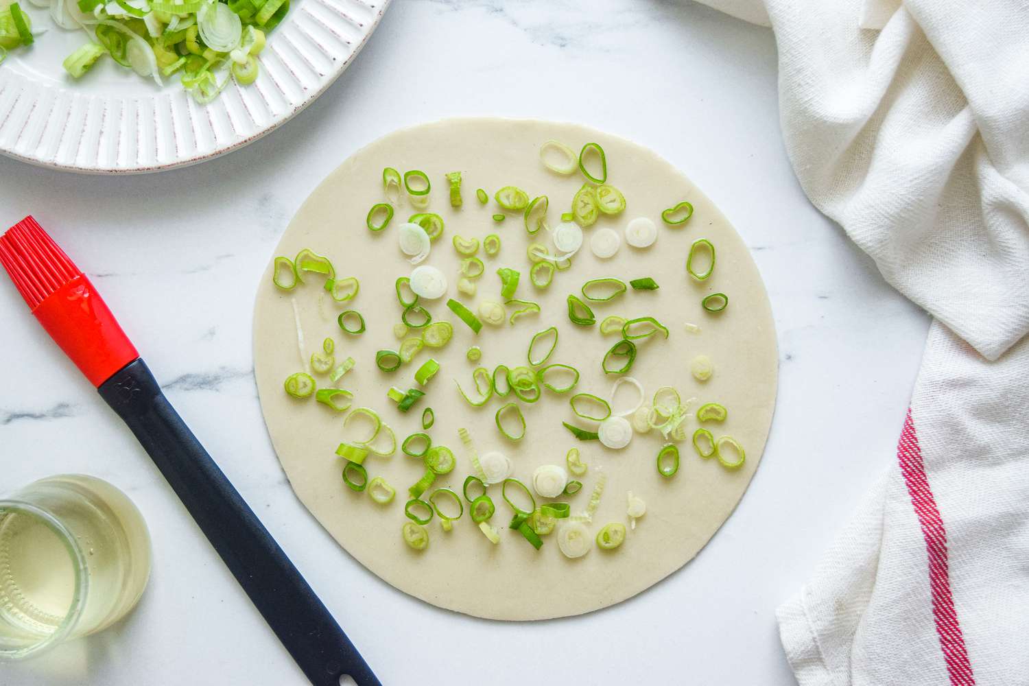 Scallions scattered over dough to make scallion pancakes.