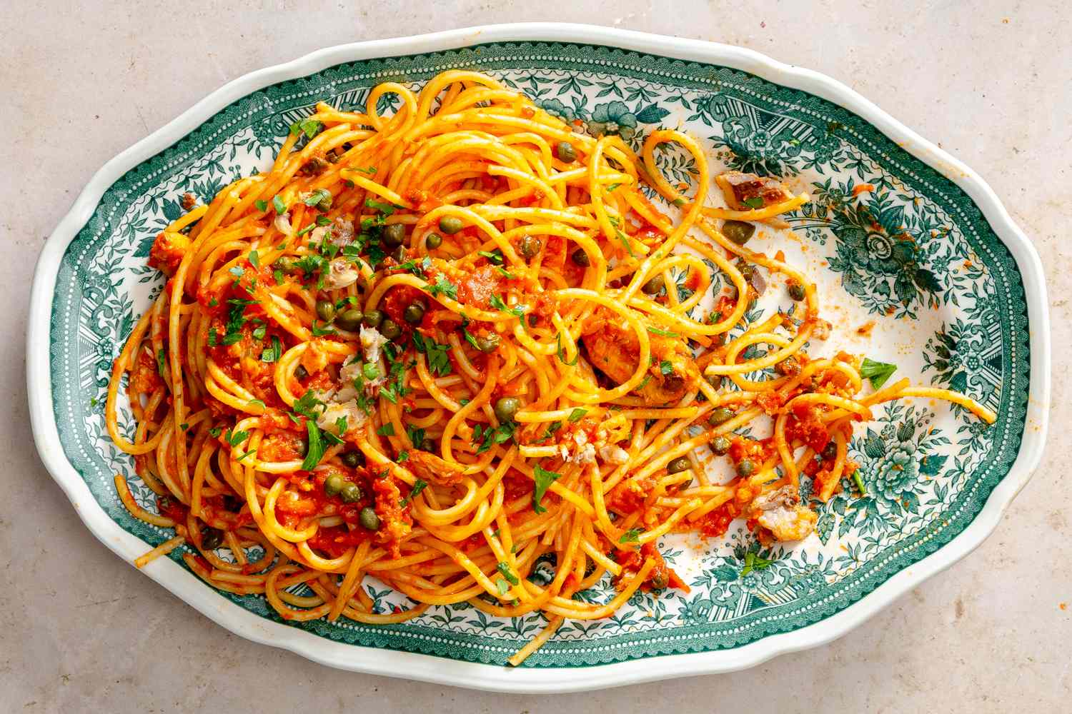 Platter of sardine pasta garnished with herbs served on a decorative dish