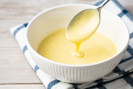 Bowl of Crème Anglaise with Some Dripping from a Spoon