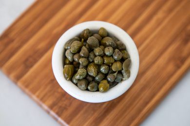 Small Bowl of Capers on a Wooden Board