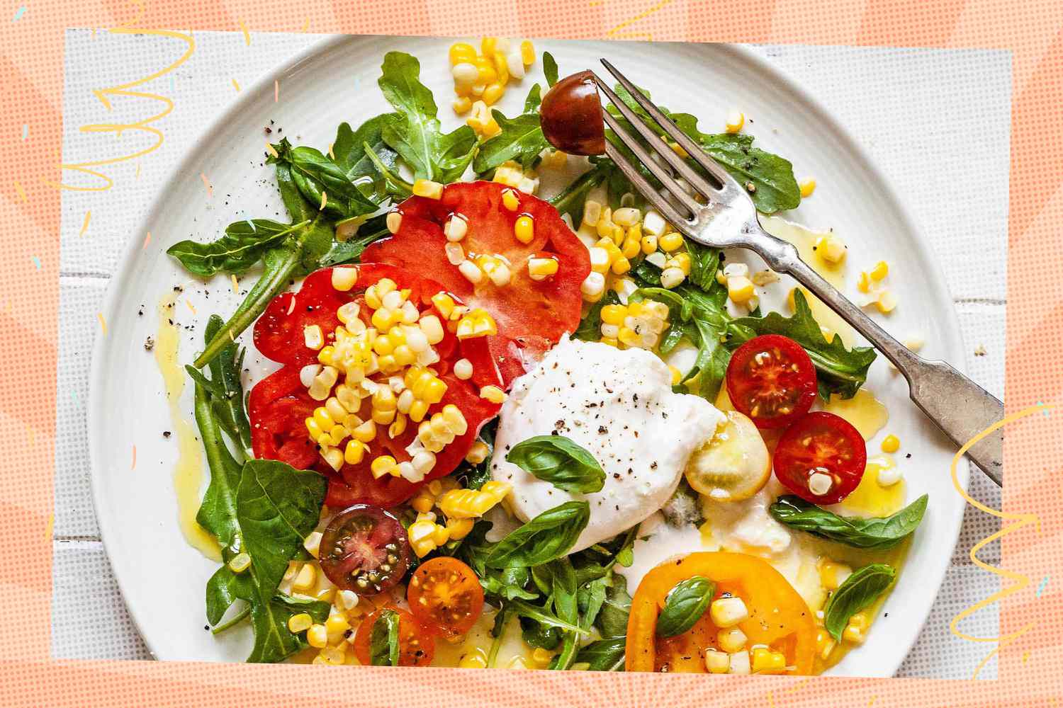 Plate of salad with tomatoes, burrata, corn, and arugula