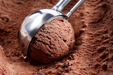A scoop of chocolate ice cream in a metal scooper