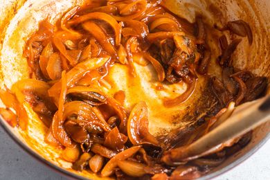 Dutch Oven with Deglazed Caramelized Onions Mixed with a Wooden Spoon, and Next to It, a Bottle of White Wine for How to Deglaze a Pan
