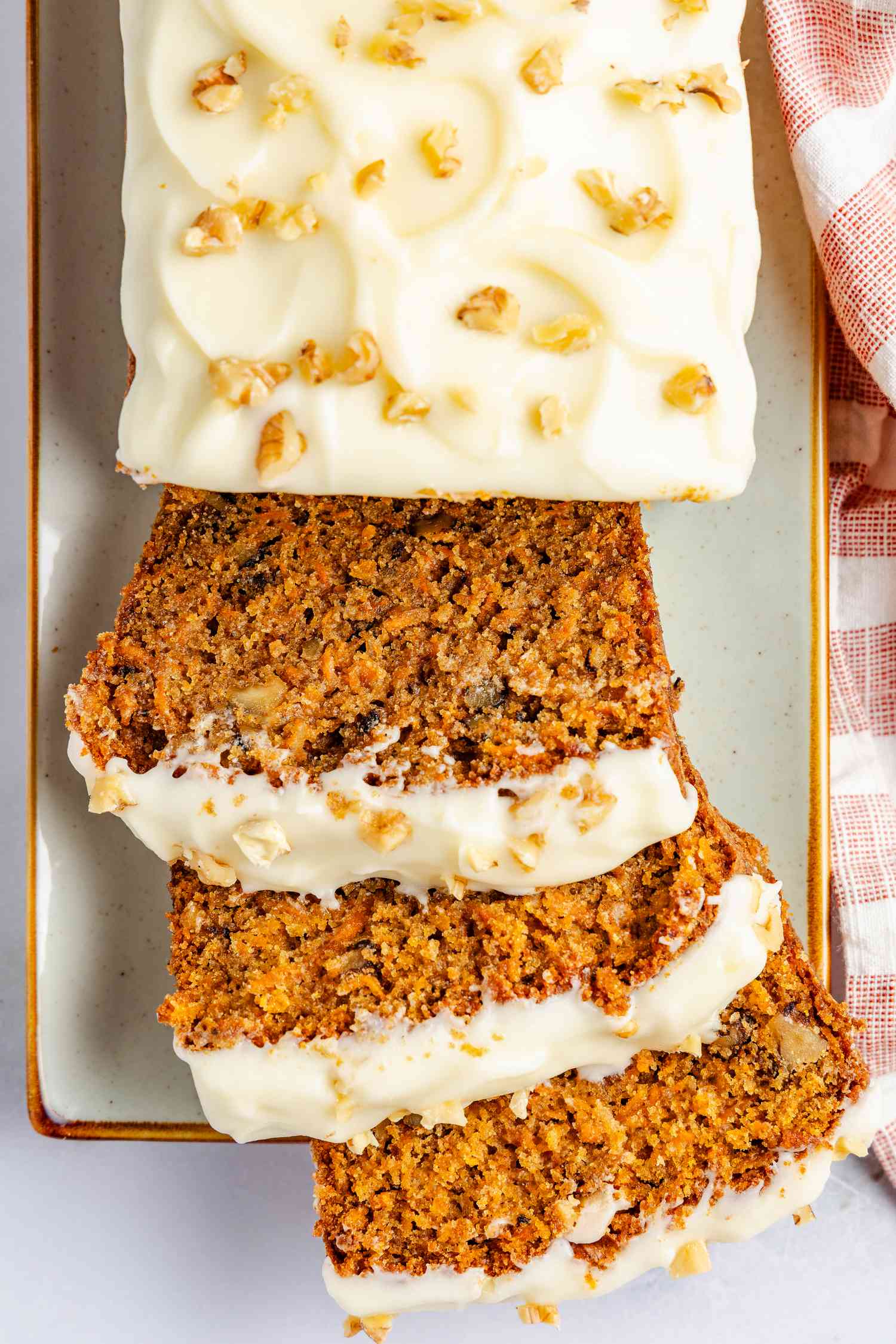 carrot cake loaf on a platter with some sliced pieces splayed onto the platter