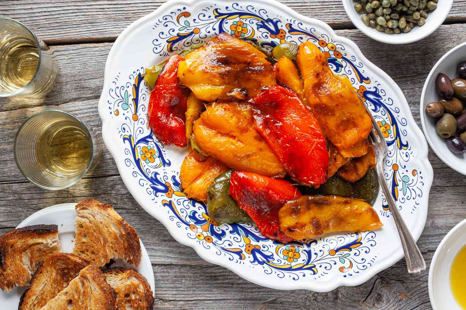 Platter of Grilled Peppers Surrounded by Olives, Capers, Olive Oil, and Toast