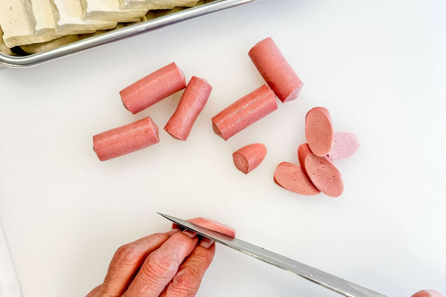 Vienna sausage cut into slices on a cutting board next to some whole pieces of sausage for homemade budae jjigae (army base soup) recipe