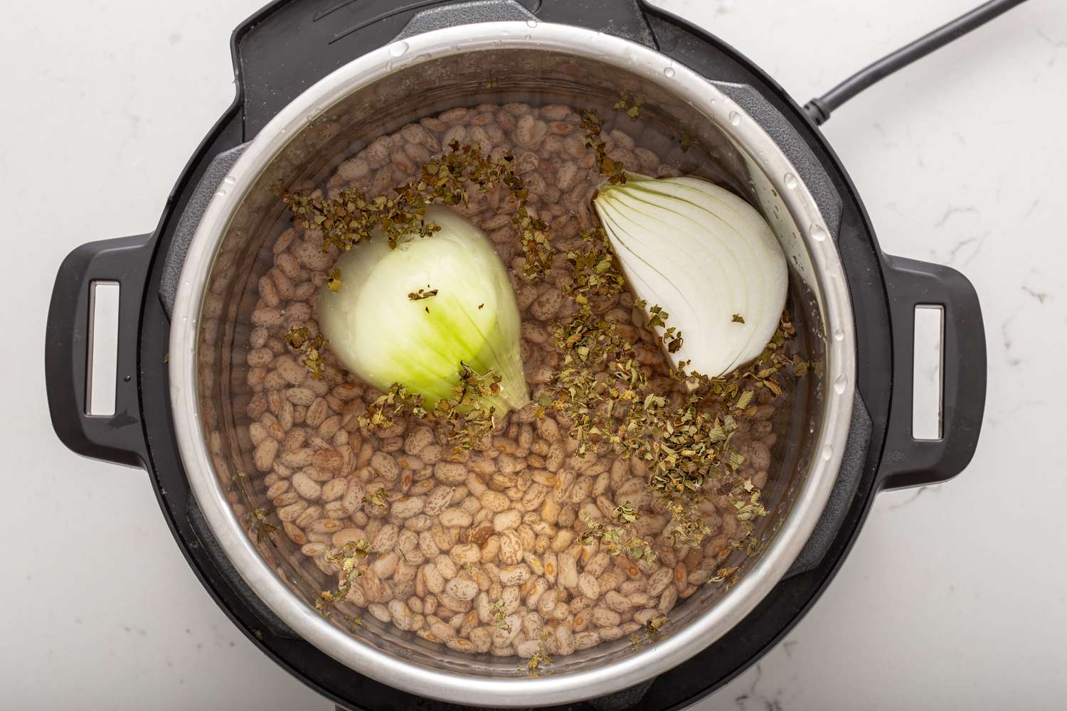 Refried beans in a pressure cooker with an onion cut in half 
