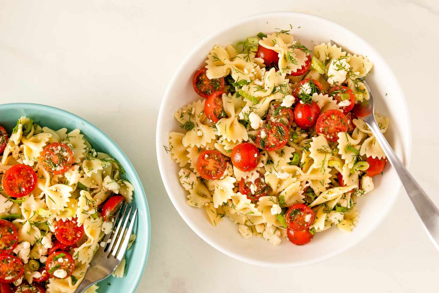 A serving of Greek pasta salad with cherry tomatoes and feta in a white bowl