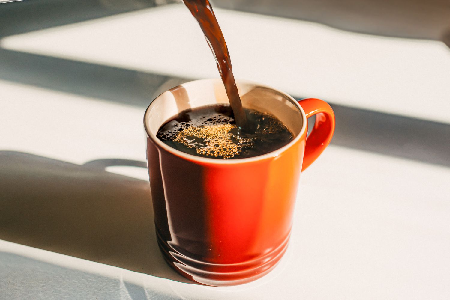 Coffee being poured into an orange mug