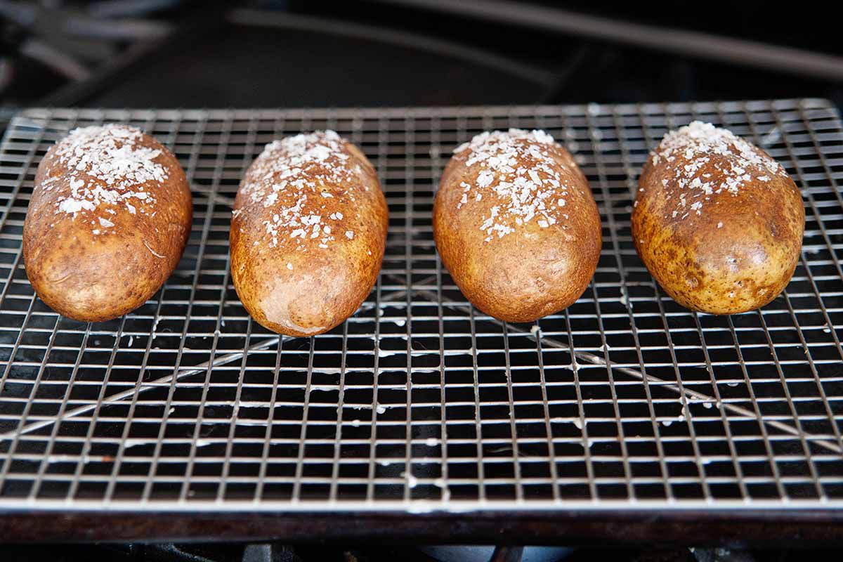 Four salted potatoes on a wire rack in the oven