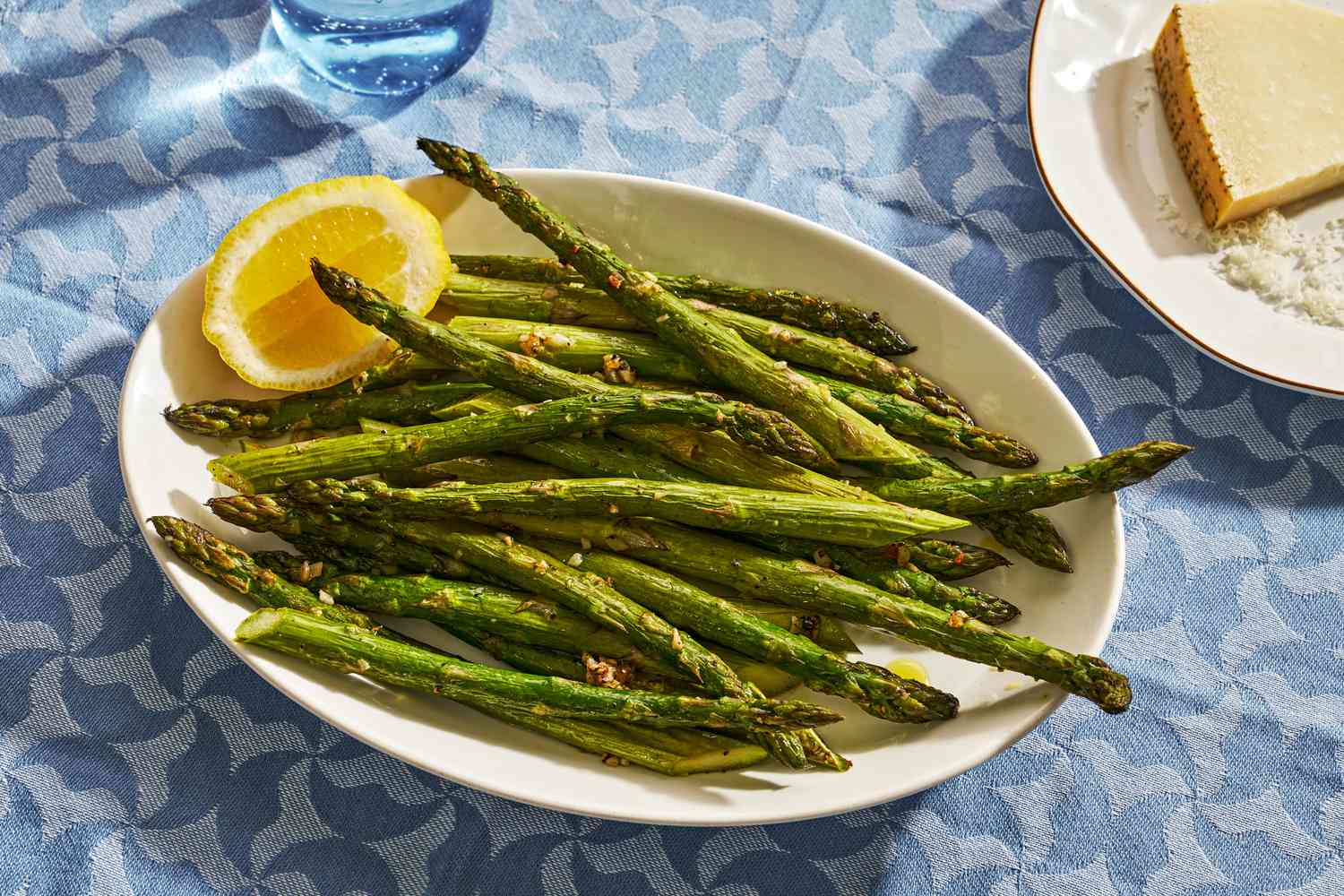 A platter of roasted asparagus garnished with half a lemon