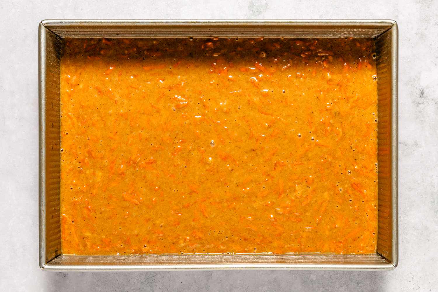 Cake batter from Easy Carrot Cake recipe in a rectangular baking pan before being baked, carrot cake preparation stage.